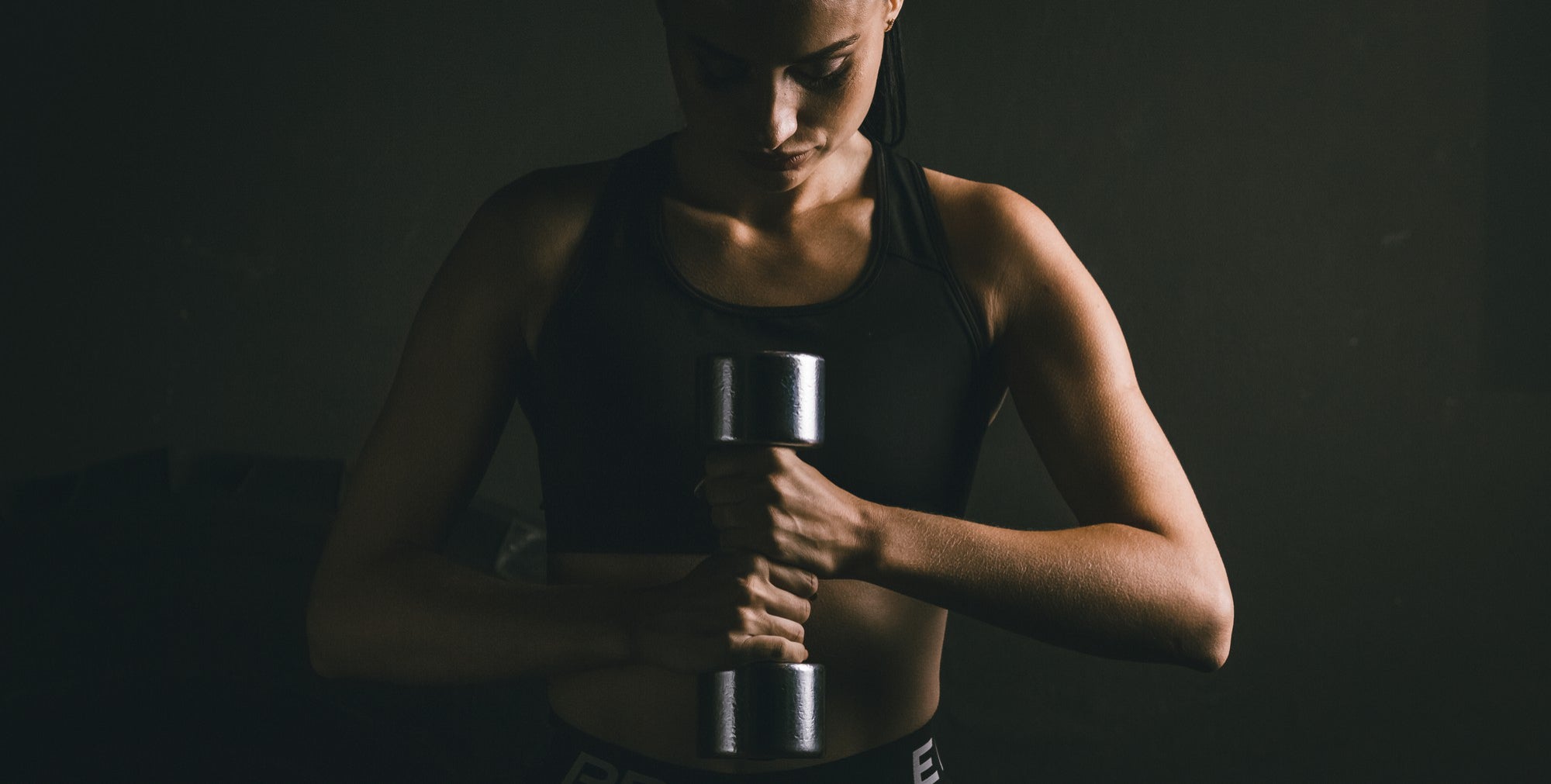 young-woman-with-dumbbells-hand-is-engaged-gym-dark-scheme-woman-is-dressed-black-top.jpg